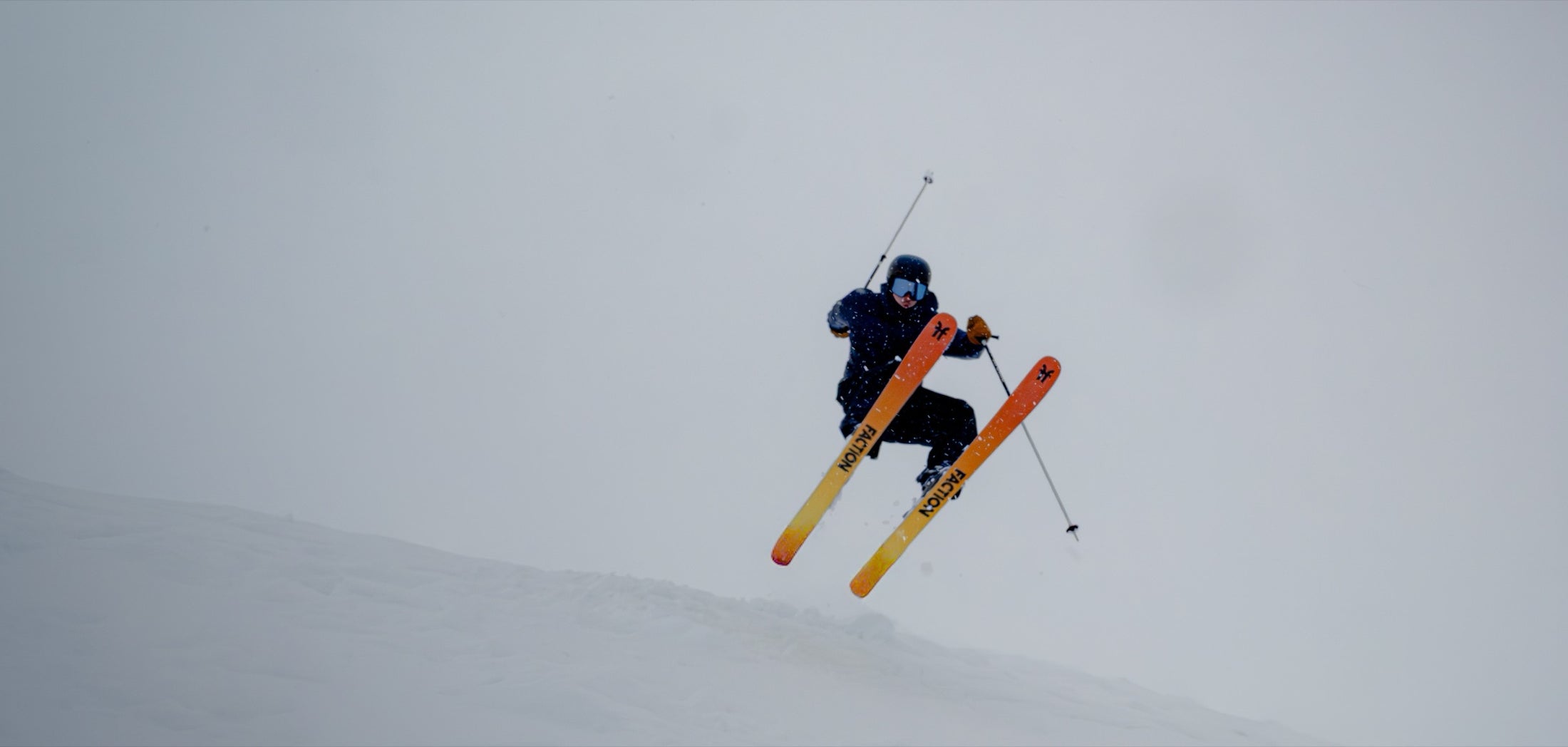 Esquiador sujetando su ski con la mano en pleno salto en Corralco, con nieve cayendo alrededor